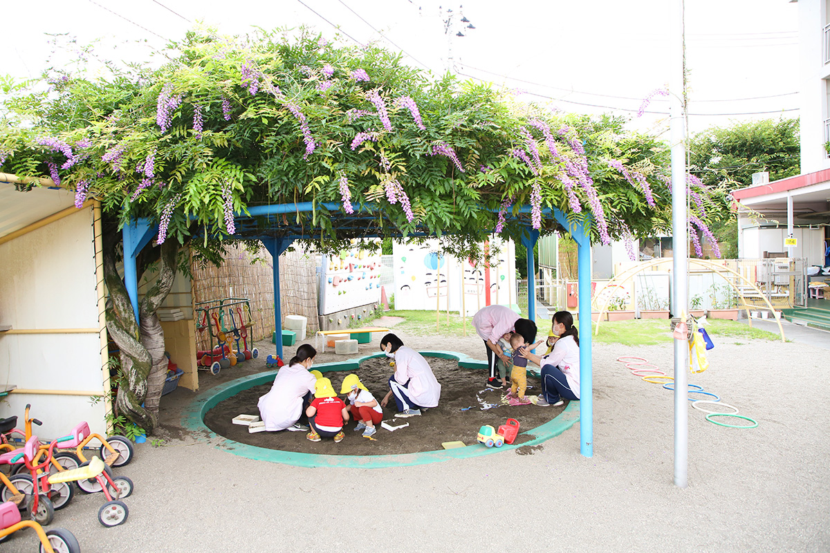 美しい藤棚の下では、1歳児がおしゃべりしながら楽しそうに砂遊び