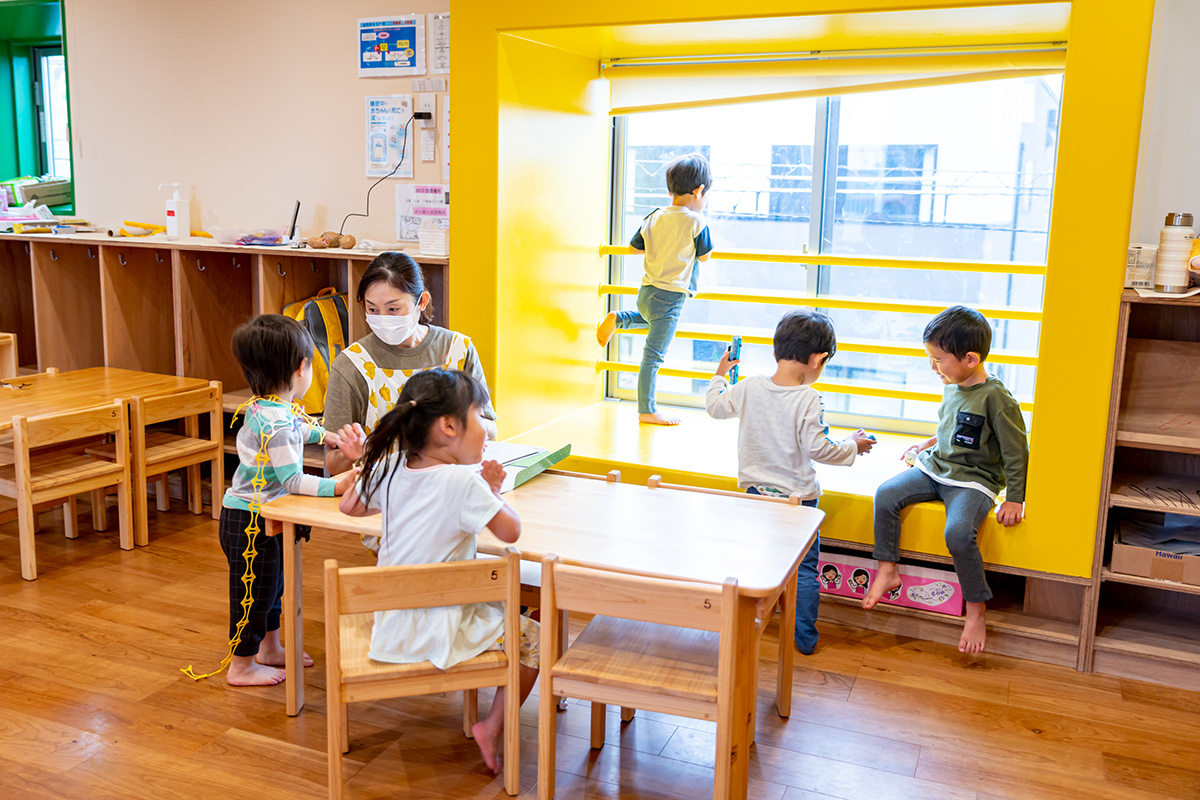解放感のある明るい保育室。窓辺でくつろぐ子どもたち。