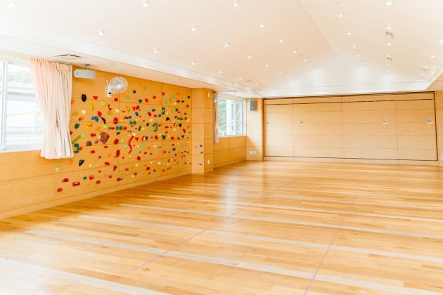 ホールの壁面にはボルダリングの遊具が。雨の日ものびのび過ごすことができる。正面奥は収納可能なステージ。