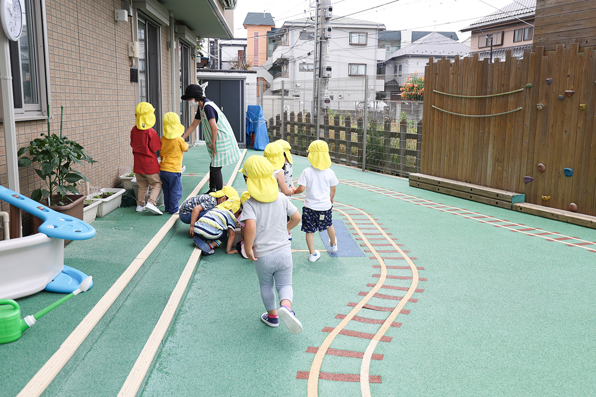 電車を見ながらのびのびと遊ぶことができる線路沿いの園庭